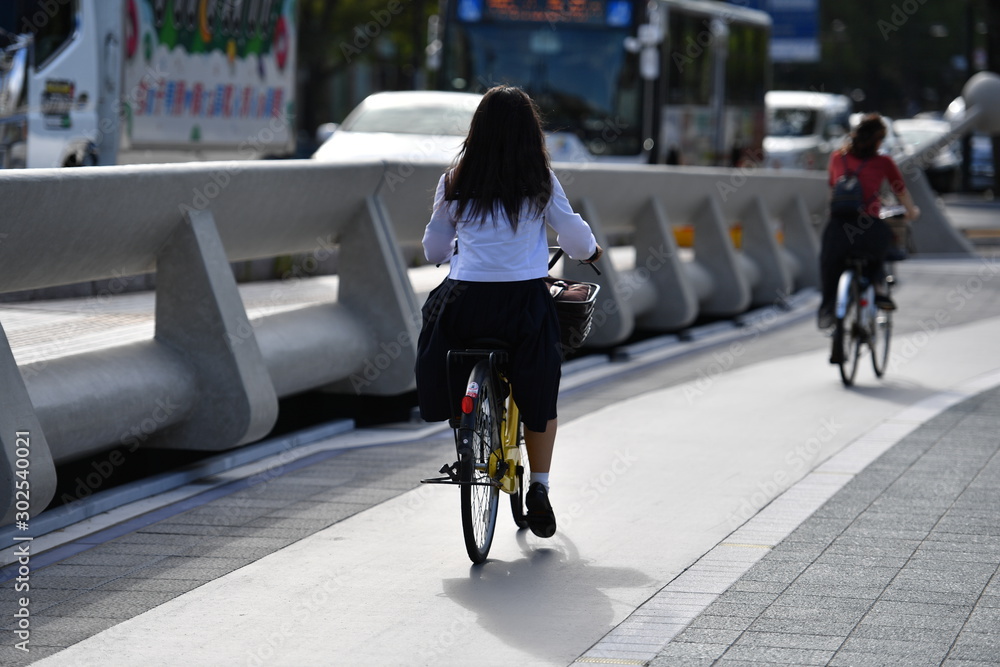 A young female student is driving over a bridge of the river Motoyasu in Hiroshima white her bicycle.