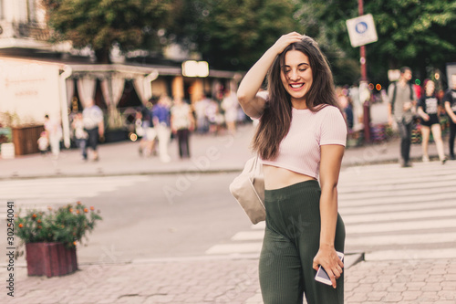 Woman using phone on the street in summer day.