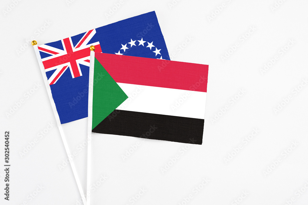 Sudan and Cook Islands stick flags on white background. High quality fabric, miniature national flag. Peaceful global concept.White floor for copy space.