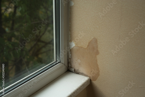 Wet spots from damp on the wall in the apartment near the window