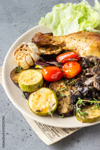 Baked chicken legs with vegetables and mushrooms with salad and thyme.