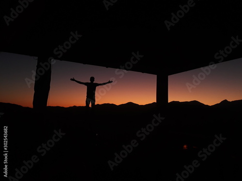 standing with arms wide open at sunset