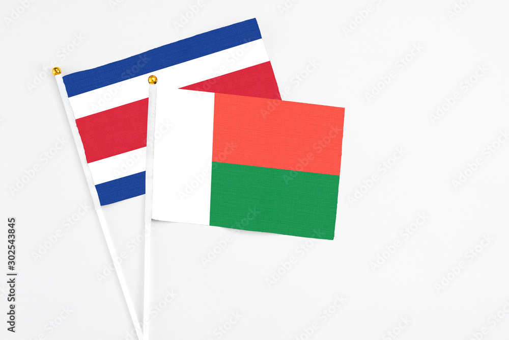 Madagascar and Costa Rica stick flags on white background. High quality fabric, miniature national flag. Peaceful global concept.White floor for copy space. Madagascar and Costa Rica stick flags on white background. High quality fabric, miniature national flag. Peaceful global concept.White floor for copy space.