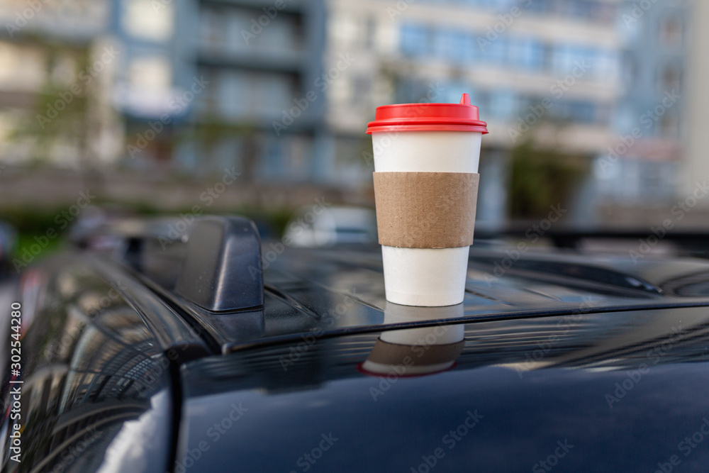 White paper coffee Cup with red lid on car roof. Paper Cup with