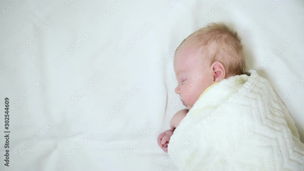 Cute baby sleeps lying on its side on a white bed sheet. Cute baby sleeps lying on its side on a white bed sheet.