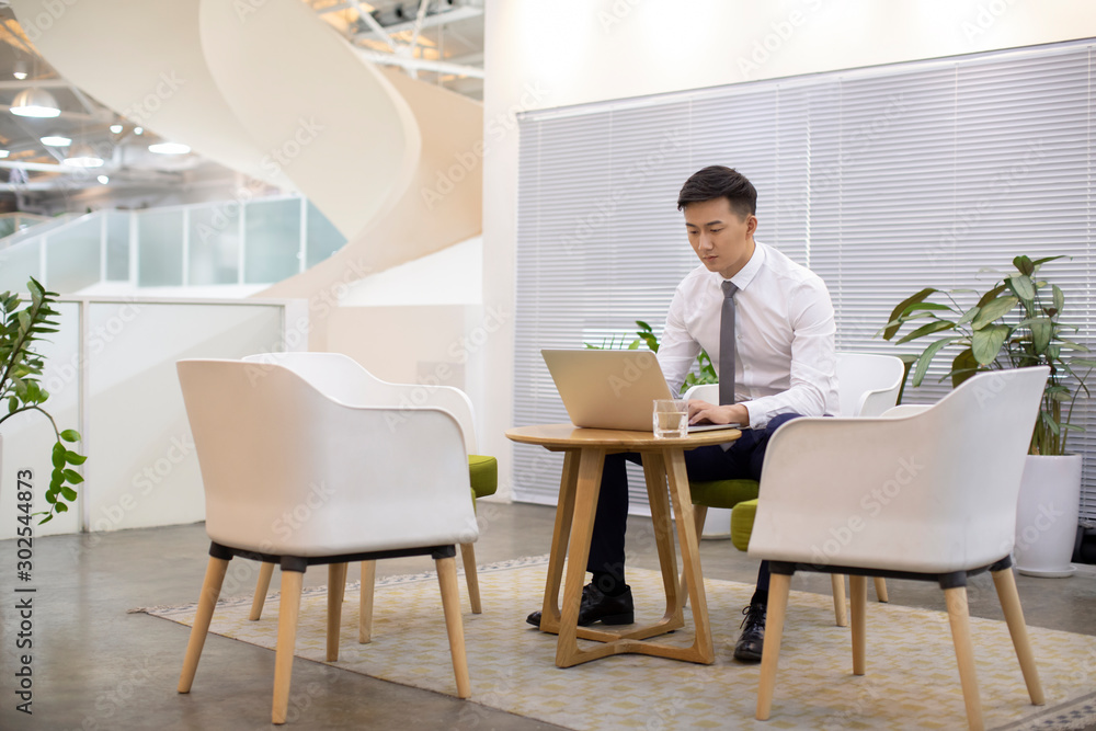 Young Chinese businessman using laptop in office Young Chinese businessman using laptop in office