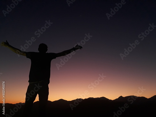 standing with arms wide open at sunset