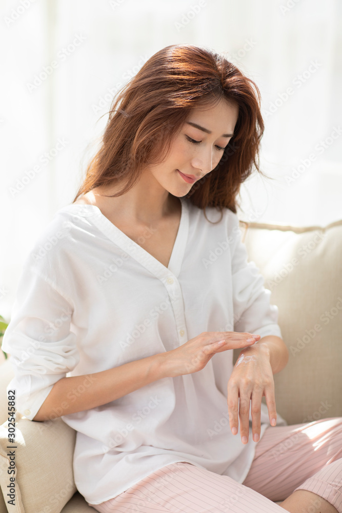 Young Chinese woman applying moisturizer at home Young Chinese woman applying moisturizer at home