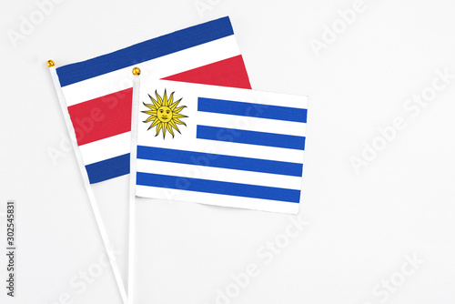 Uruguay and Costa Rica stick flags on white background. High quality fabric, miniature national flag. Peaceful global concept.White floor for copy space. photo