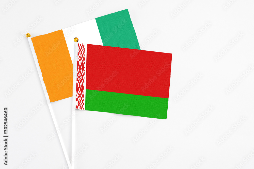 Fototapeta premium Belarus and Cote D'Ivoire stick flags on white background. High quality fabric, miniature national flag. Peaceful global concept.White floor for copy space.