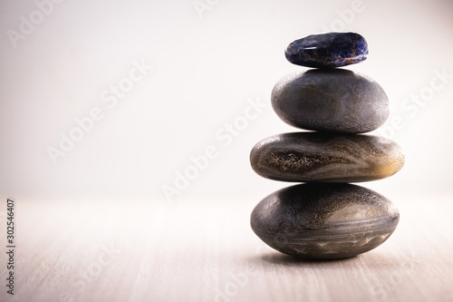 Pile of spa stones on the table against a white background, space for text. Zen stones for meditation and mystical healing.