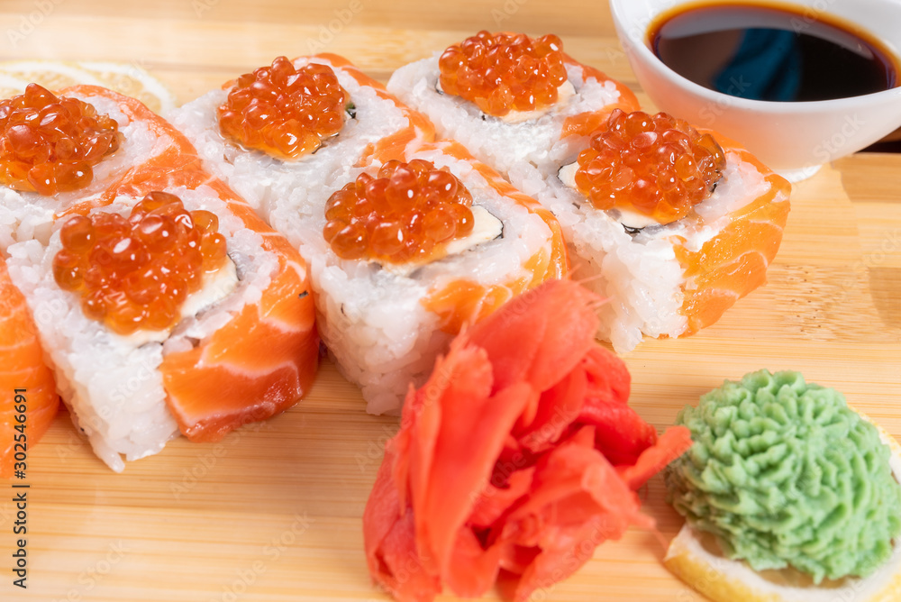 Sushi, with curd cheese, salmon and caviar. On the plank. On a red background.