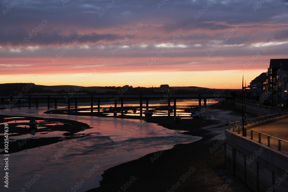 River Adur winds is way to the sea through Shoreham by Sea during a colourful sunset and reflection