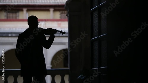  silhouette of a violinist playing the violin in an old building