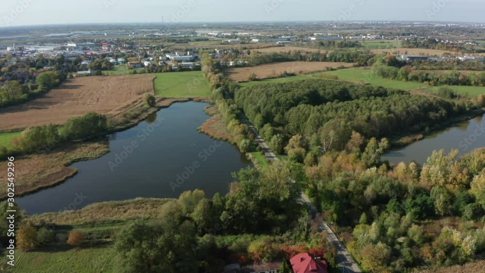 Aerial view of a car driving through a forest and lake in the countryside. Beautiful road in Poland, a suburb of Warsaw. Driving on a mountain road. Road trip. Drone Shot 4K. Aerial view of a car driving through a forest and lake in the countryside. Beautiful road in Poland, a suburb of Warsaw. Driving on a mountain road. Road trip. Drone Shot 4K.