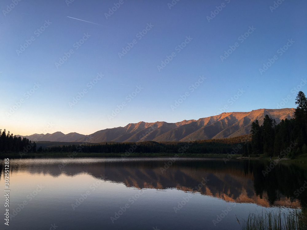 Mountain and forest reflection on lake at sunset