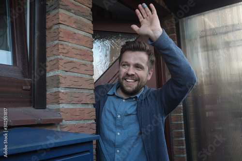 Obraz na plátně Man waving with a friendly cheerful smile to his new neighbours.