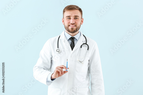 Doctor with syringe on light background © Pixel-Shot
