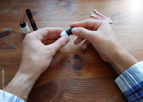 A man in a plaid shirt cleans an iqos electronic cigarette. First-person photo. photo