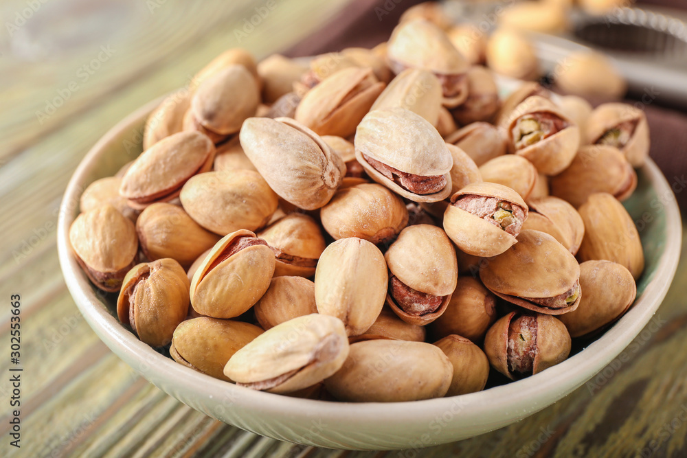Bowl with tasty pistachio nuts on table, closeup Bowl with tasty pistachio nuts on table, closeup