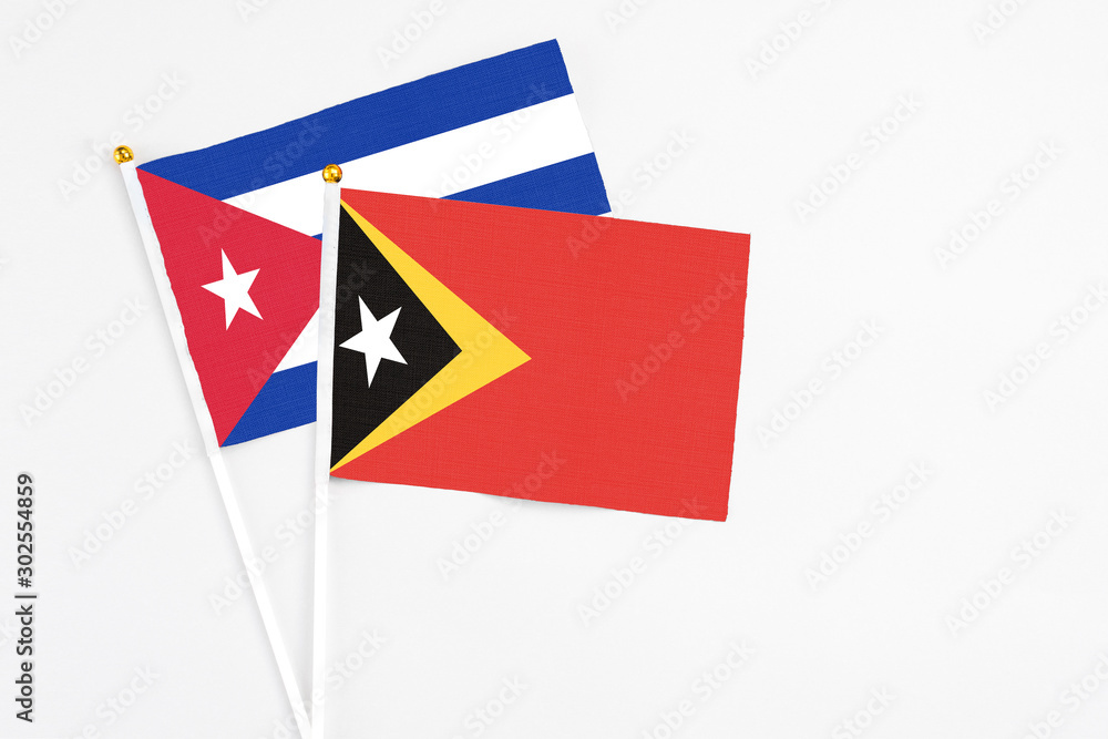 East Timor and Cuba stick flags on white background. High quality fabric, miniature national flag. Peaceful global concept.White floor for copy space. East Timor and Cuba stick flags on white background. High quality fabric, miniature national flag. Peaceful global concept.White floor for copy space.