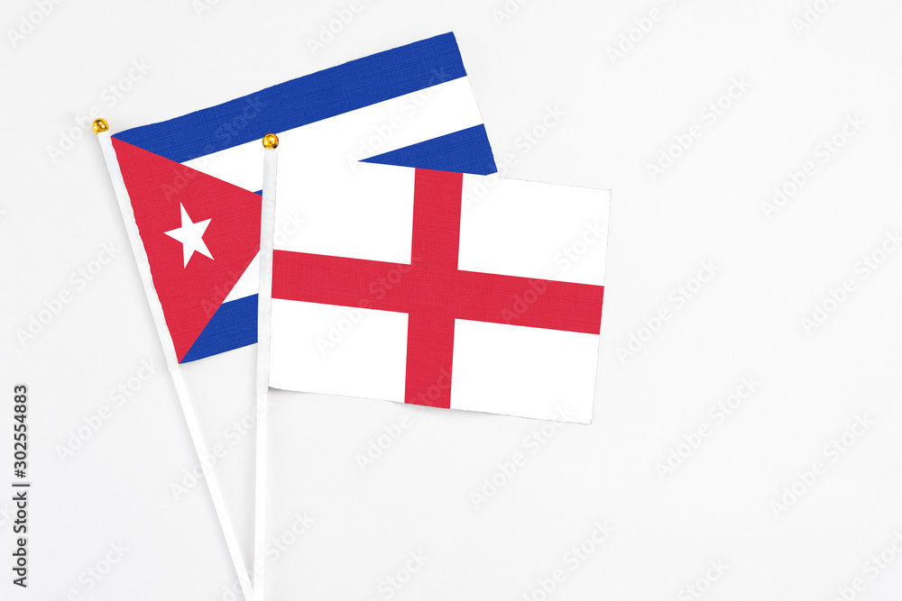 England and Cuba stick flags on white background. High quality fabric, miniature national flag. Peaceful global concept.White floor for copy space.