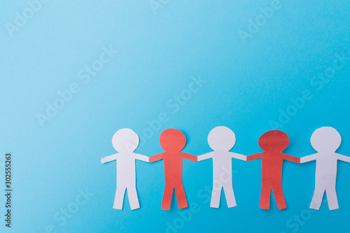 Red and white figures cut out of paper. Blue background. Copy space