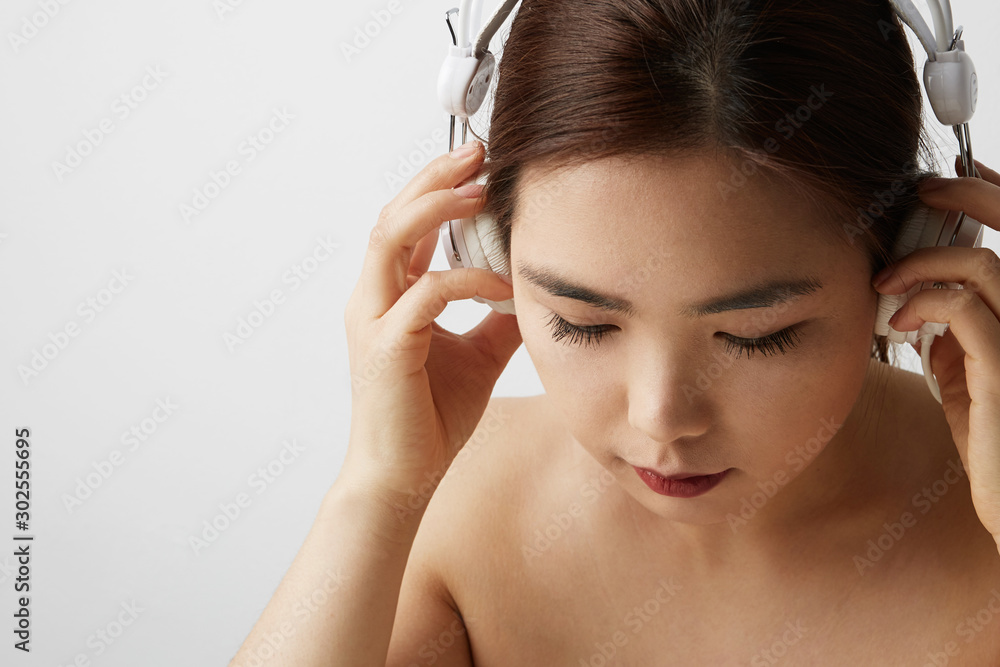 Side portrait of Chinese woman posing on the white background with big earphones. Isolated.