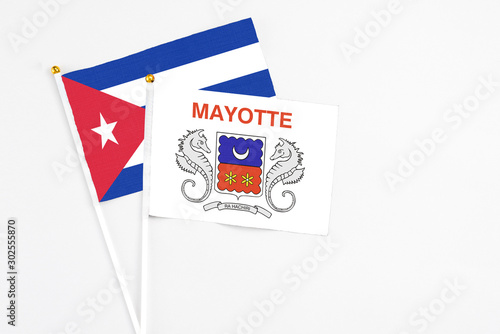 Mayotte and Cuba stick flags on white background. High quality fabric, miniature national flag. Peaceful global concept.White floor for copy space.