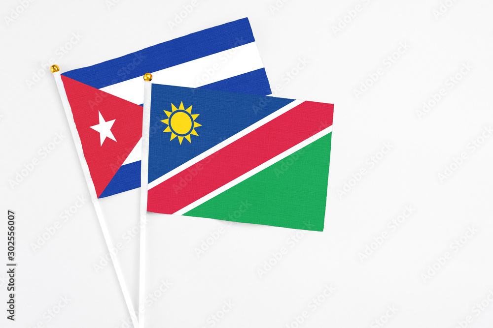 Namibia and Cuba stick flags on white background. High quality fabric, miniature national flag. Peaceful global concept.White floor for copy space.