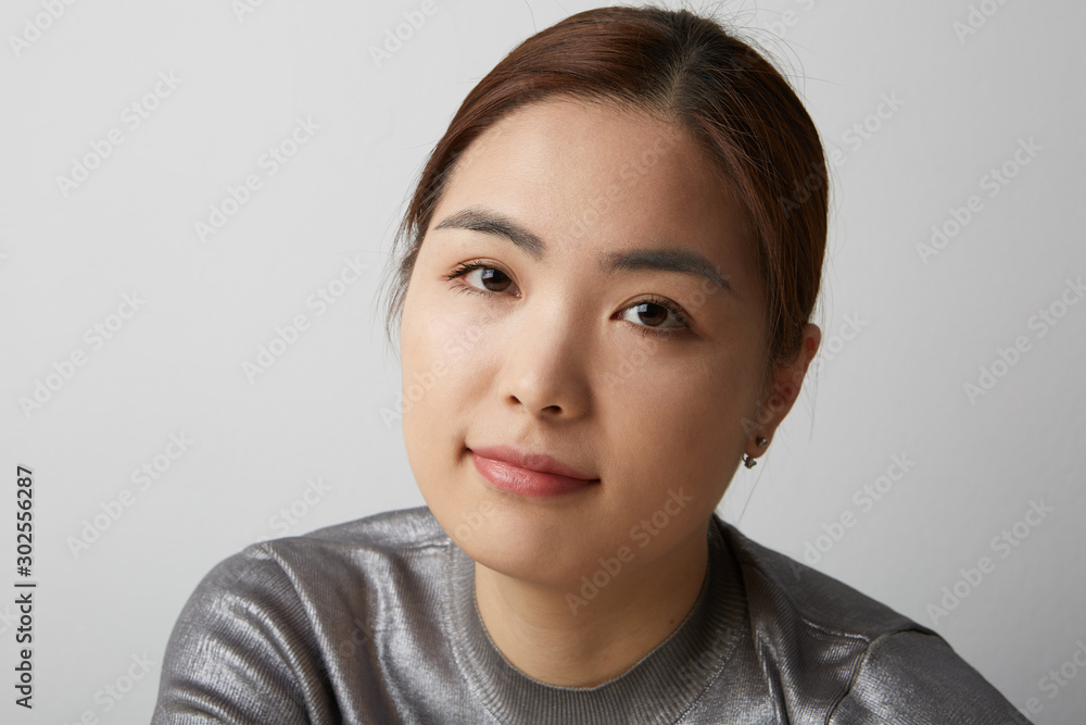 Close-up portrait of Chinese woman posing on the white background with her hands crossed. Isolated. Close-up portrait of Chinese woman posing on the white background with her hands crossed. Isolated.