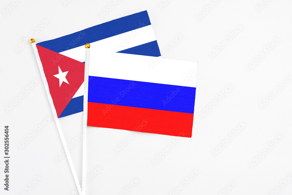 Russia and Cuba stick flags on white background. High quality fabric, miniature national flag. Peaceful global concept.White floor for copy space. Russia and Cuba stick flags on white background. High quality fabric, miniature national flag. Peaceful global concept.White floor for copy space.