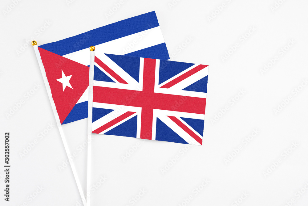 United Kingdom and Cuba stick flags on white background. High quality fabric, miniature national flag. Peaceful global concept.White floor for copy space. United Kingdom and Cuba stick flags on white background. High quality fabric, miniature national flag. Peaceful global concept.White floor for copy space.