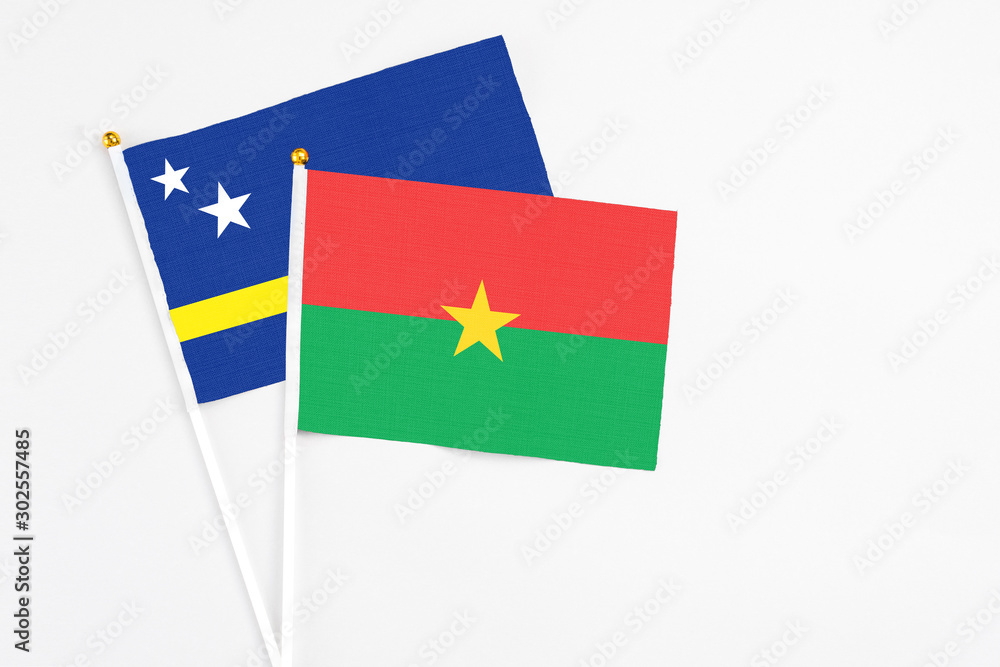 Burkina Faso and Curacao stick flags on white background. High quality fabric, miniature national flag. Peaceful global concept.White floor for copy space.