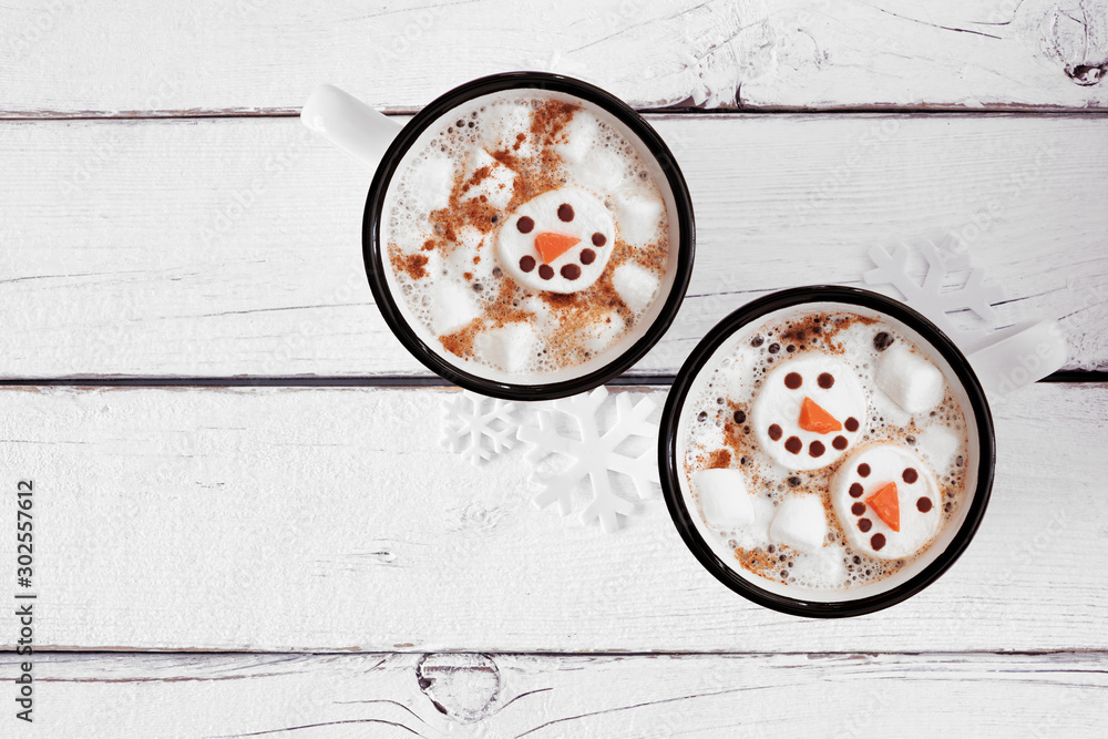 Two cups of holiday hot chocolate with snowman marshmallows. Top view on a white wood background. - obrazy, fototapety, plakaty 