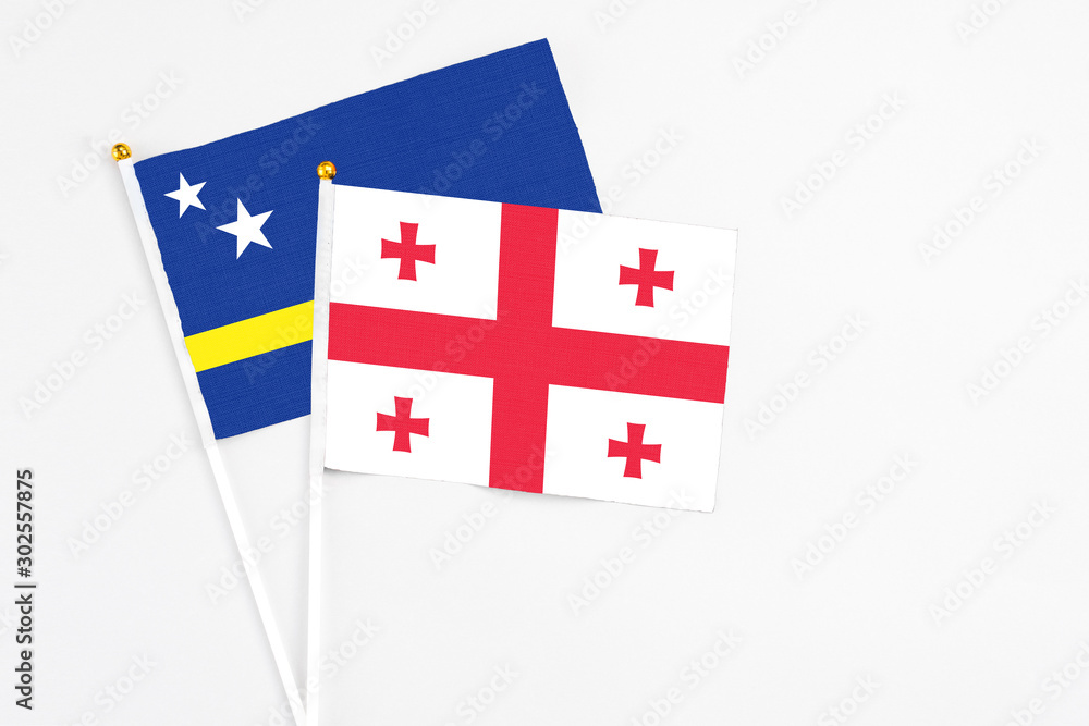 Georgia and Curacao stick flags on white background. High quality fabric, miniature national flag. Peaceful global concept.White floor for copy space.