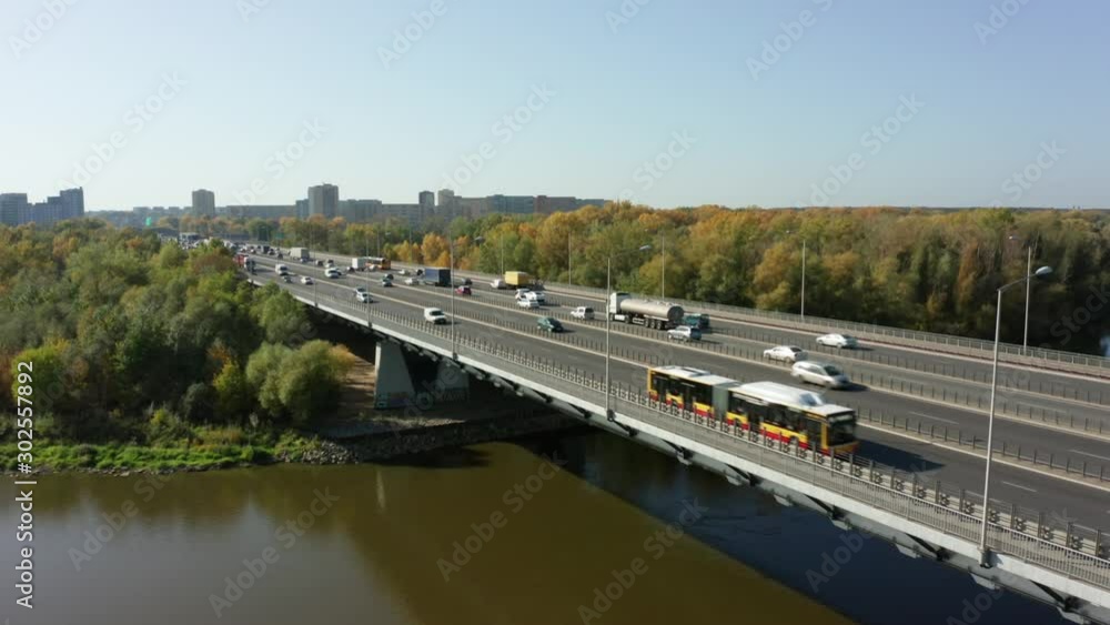 Drone shot on a four-lane highway with vans and city transport. The highway passes through the river and leads to the center of Warsaw, Poland. Drone shot on a four-lane highway with vans and city transport. The highway passes through the river and leads to the center of Warsaw, Poland.