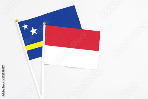 Indonesia and Curacao stick flags on white background. High quality fabric, miniature national flag. Peaceful global concept.White floor for copy space. photo