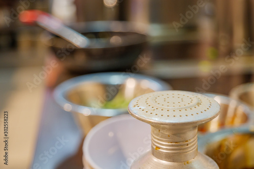 Close up and macro view at top of metal white Thai pepper shaker or grinder and blur background of kitchen in restaurant.