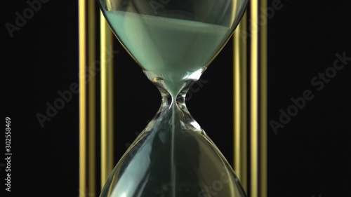 Extreme close up view of sand flowing through an hour glass. Super closeup of hourglass clock middle. Classic sandglass timer countdown.