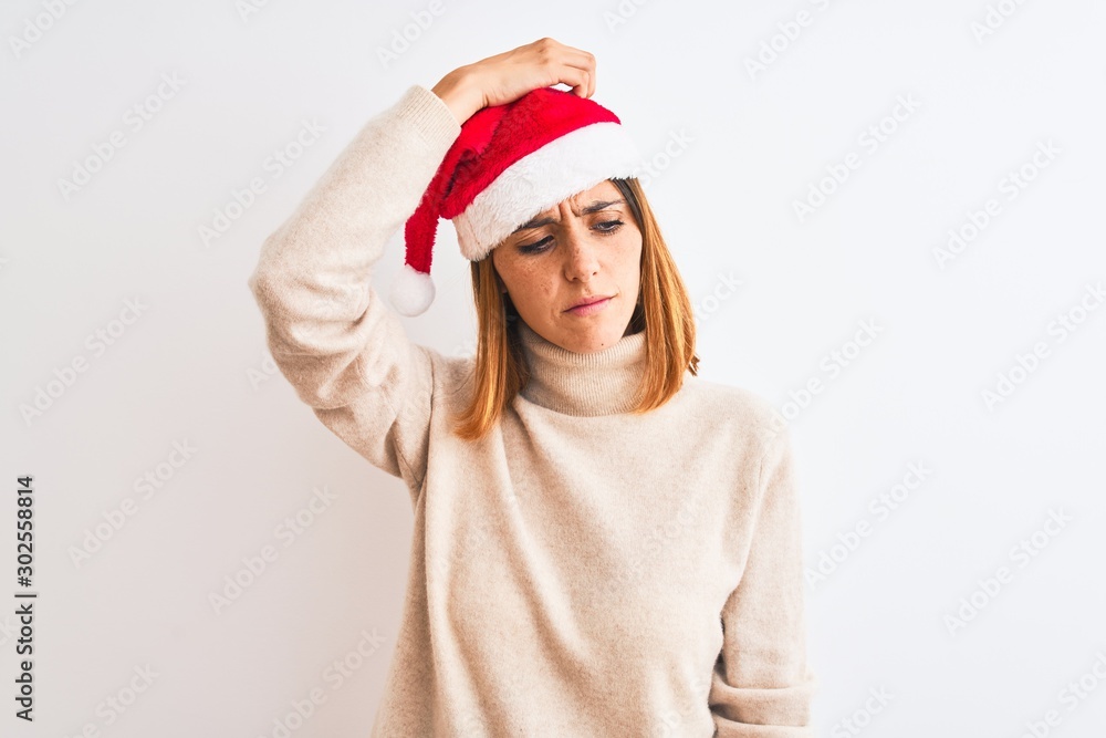 Beautiful redhead woman wearing christmas hat over isolated background confuse and wondering about question. Uncertain with doubt, thinking with hand on head. Pensive concept. Beautiful redhead woman wearing christmas hat over isolated background confuse and wondering about question. Uncertain with doubt, thinking with hand on head. Pensive concept.