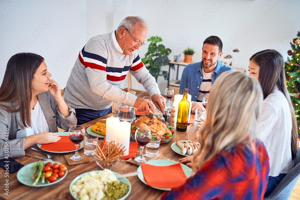 Beautiful family meeting smiling happy and confident. Carving roasted turkey celebrating Christmas at home