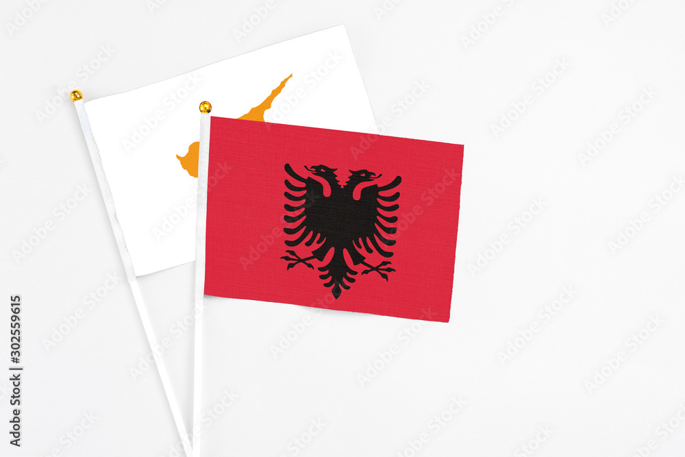 Albania and Cyprus stick flags on white background. High quality fabric, miniature national flag. Peaceful global concept.White floor for copy space.