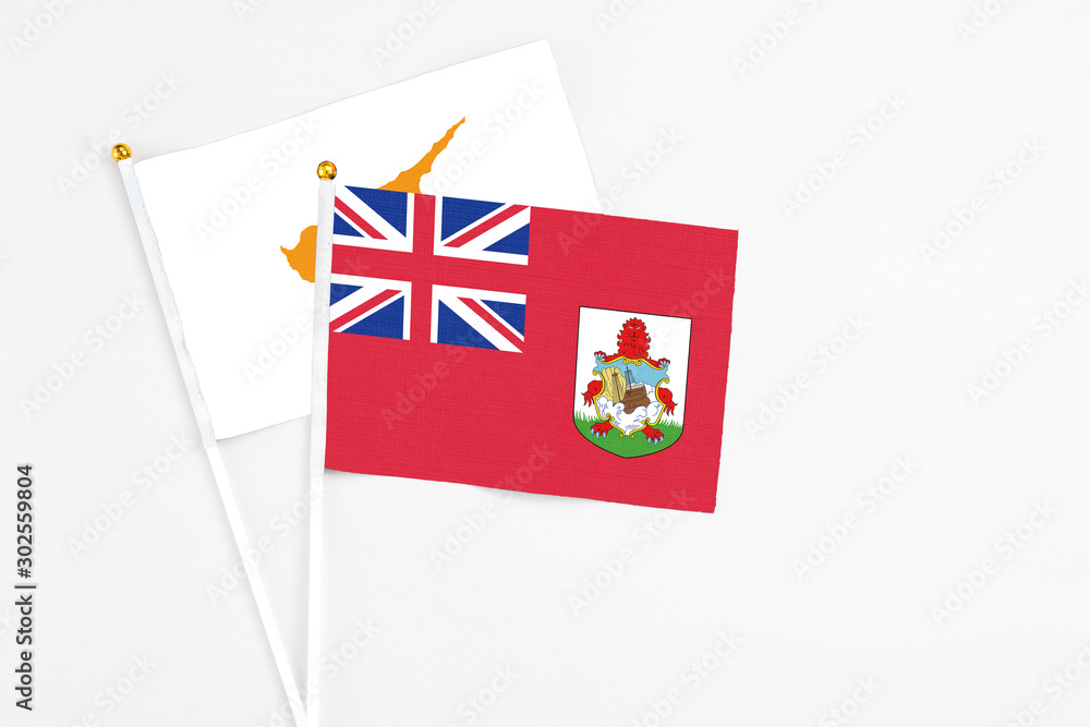 Fototapeta premium Bermuda and Cyprus stick flags on white background. High quality fabric, miniature national flag. Peaceful global concept.White floor for copy space.