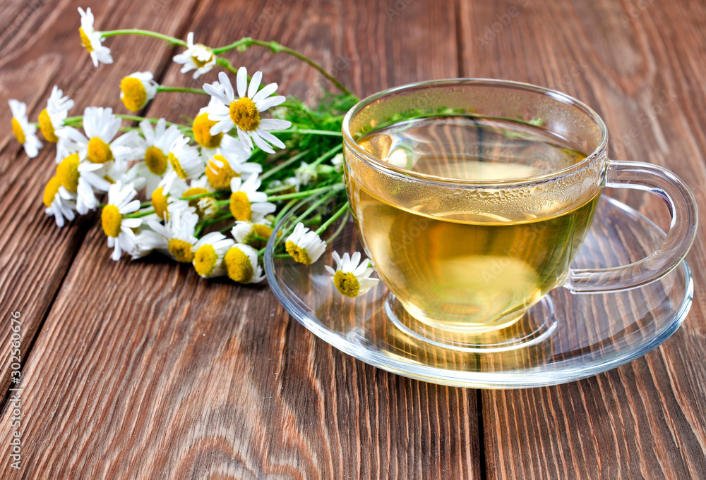 Green calming herbal tea with natural fresh chamomile flowers on a wooden background. Green calming herbal tea with natural fresh chamomile flowers on a wooden background.