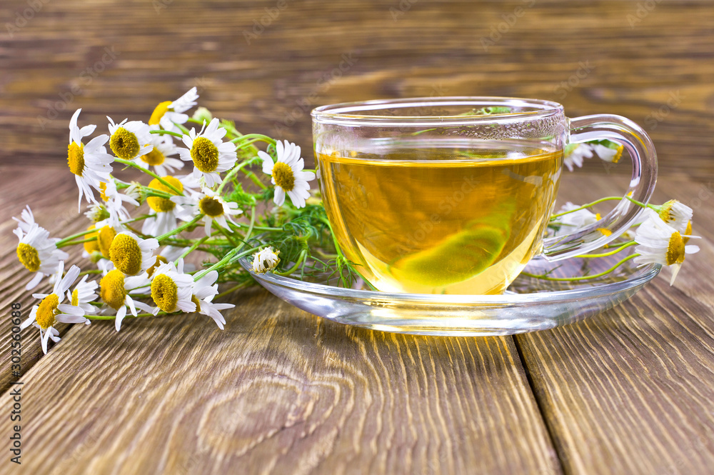 Green calming herbal tea with natural fresh chamomile flowers on a wooden background. Green calming herbal tea with natural fresh chamomile flowers on a wooden background.