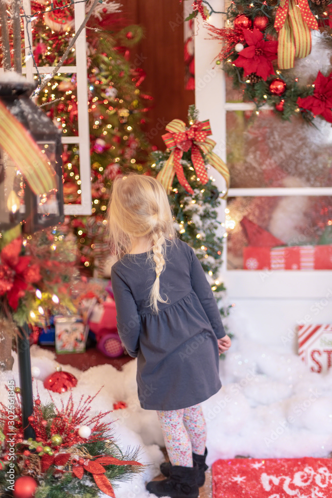 Cute little blonde girl admiring Christmas light display - vertical