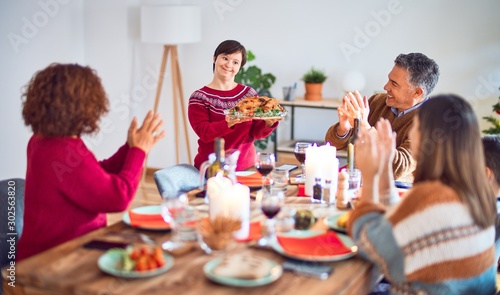 Beautiful family smiling happy and confident. One of them standing showing roasted turkey celebrating thanksgiving day at home