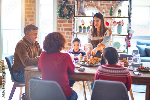 Beautiful family smiling happy and confident. One of them curving roasted turkey celebrating christmas at home © Krakenimages.com