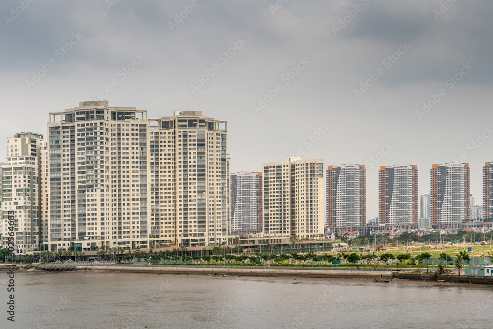 Ho Chi Minh City, Vietnam - March 12, 2019: Song Sai Gon river. High rise  apartment buildings form skyline in Binh Trung Tay neighborhood accross the  brown river under gray cloudscape. Stock